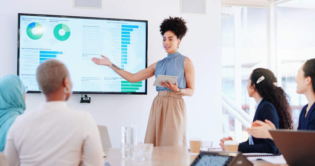 Frau im Business-Meeting erläutert Ihre Strategie und erntet Applaus.